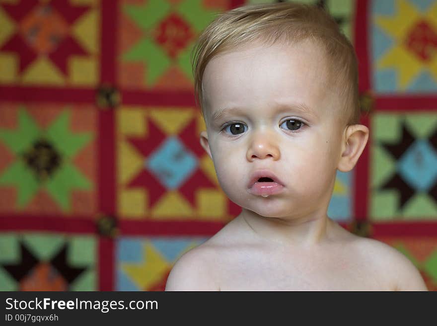 Image of cute toddler with a quilt in the background