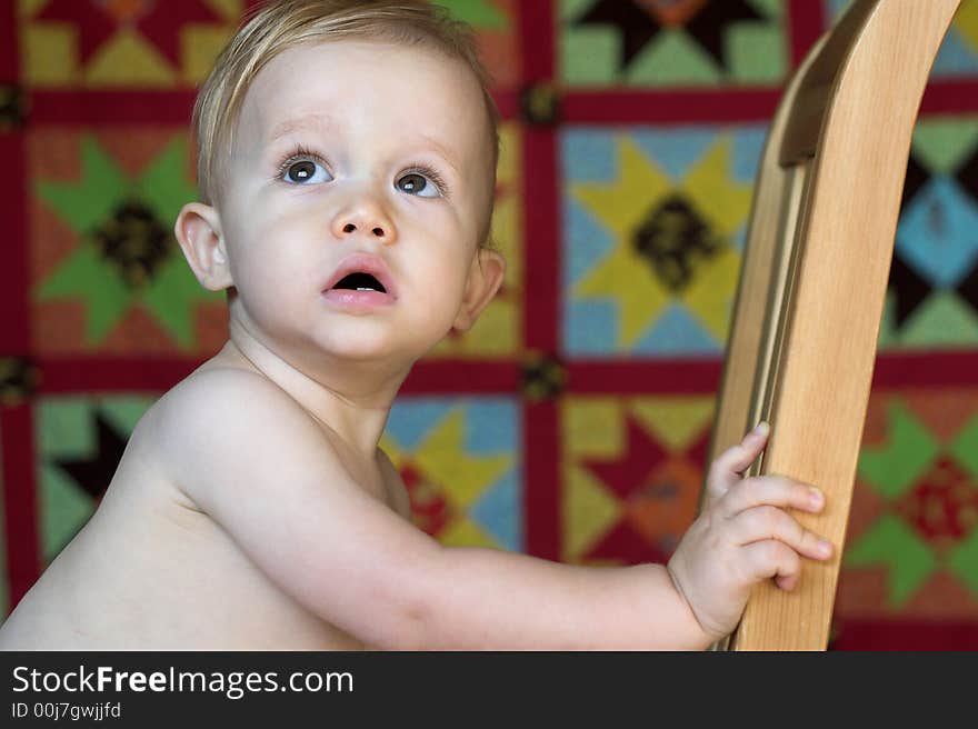 Image of cute toddler with a quilt in the background