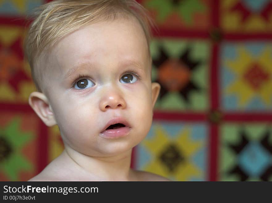 Image of cute toddler with a quilt in the background