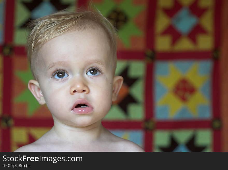 Image of cute toddler with a quilt in the background