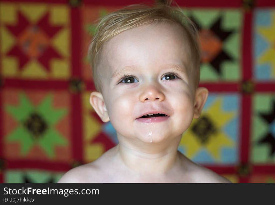 Image of cute toddler with a quilt in the background