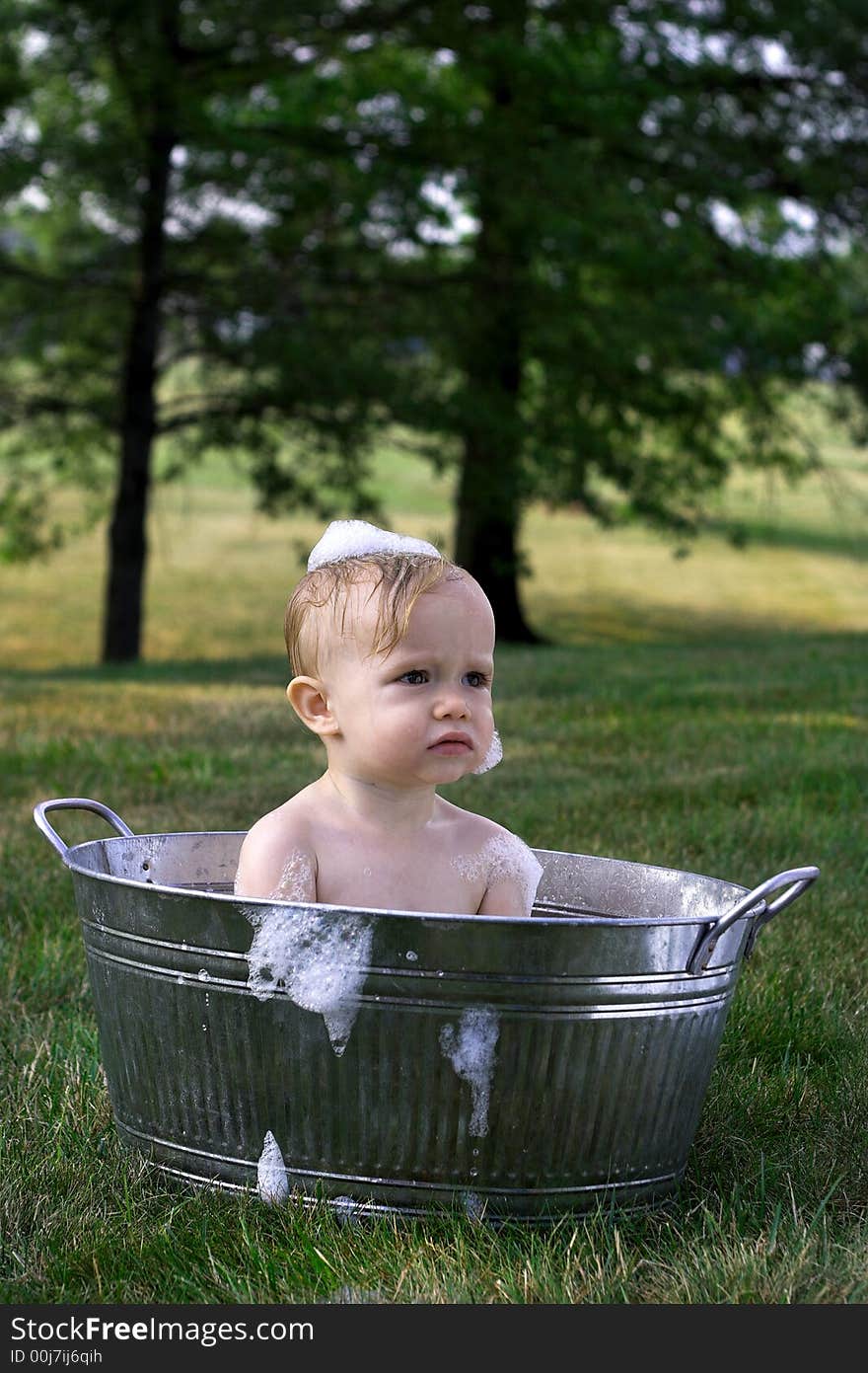 Image of cute toddler sitting in a tub outside. Image of cute toddler sitting in a tub outside