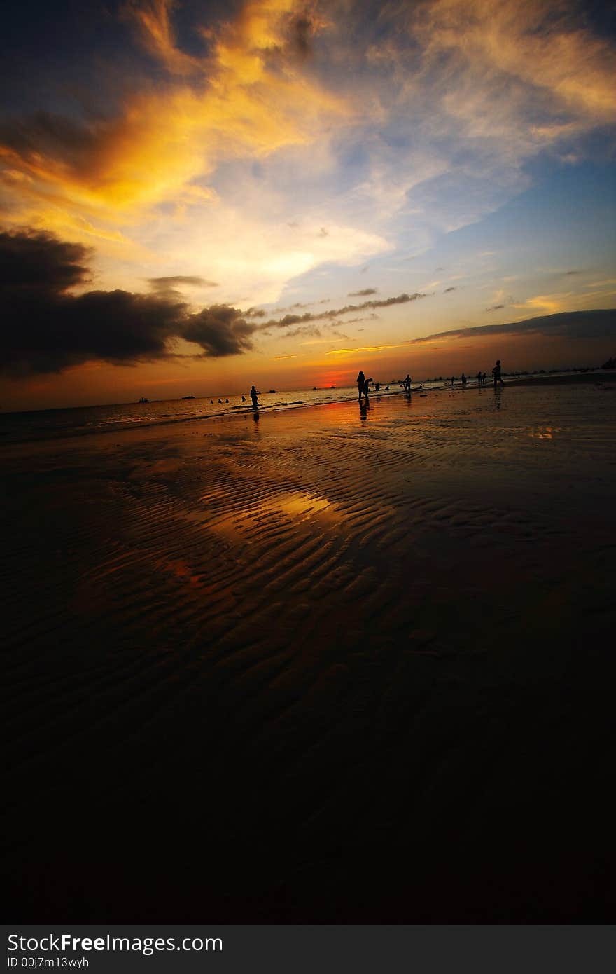 Sunset in a tropical beach in the philippines. silhouettes of people, beautiful cloud formations and sand ripples shown. Sunset in a tropical beach in the philippines. silhouettes of people, beautiful cloud formations and sand ripples shown