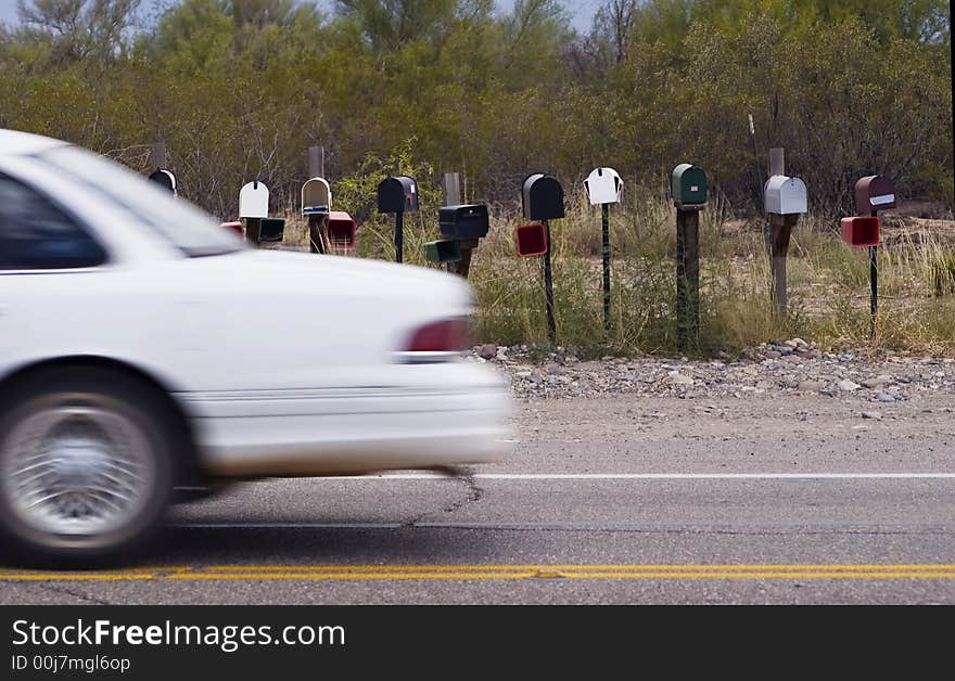 White car passes a set of rural mailboxes. White car passes a set of rural mailboxes