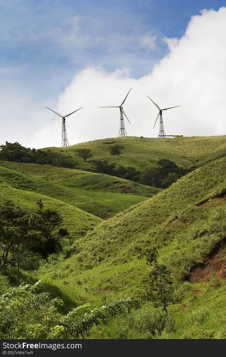 Three energy generating windmills on a green hilltop. Three energy generating windmills on a green hilltop.