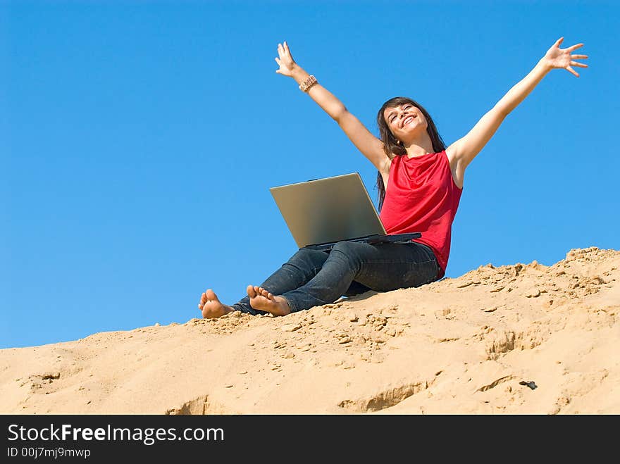 The joyful young woman with a computer on sand. The joyful young woman with a computer on sand