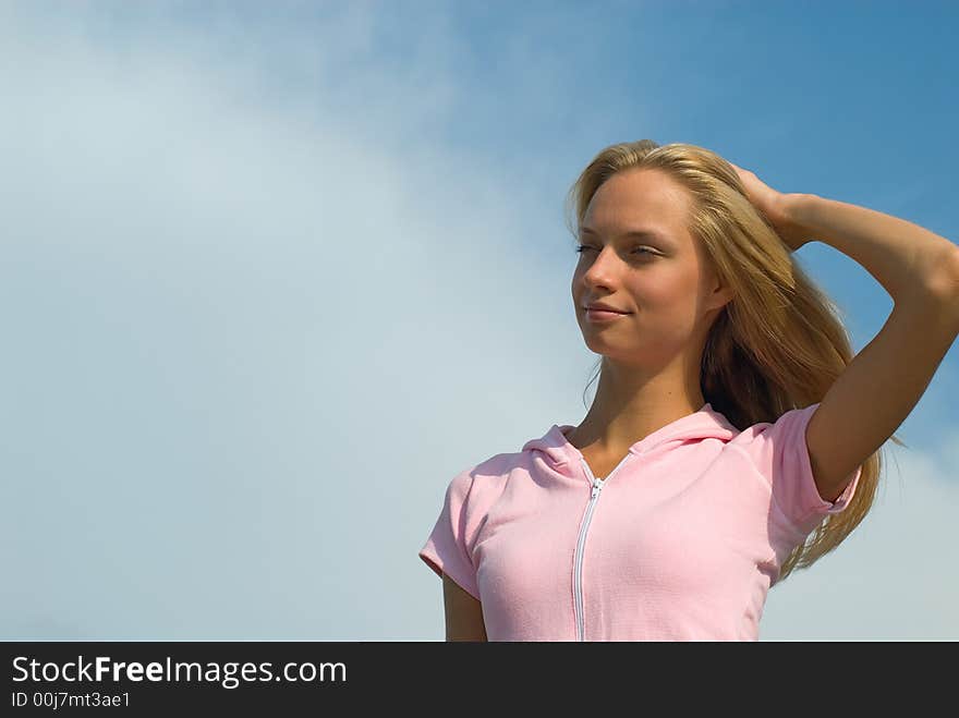 The young beautiful woman reflects on a background of blue sky. The young beautiful woman reflects on a background of blue sky