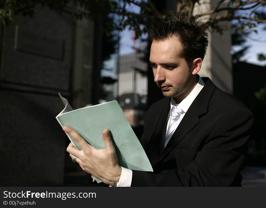 A business man in the city reading a book. A business man in the city reading a book.