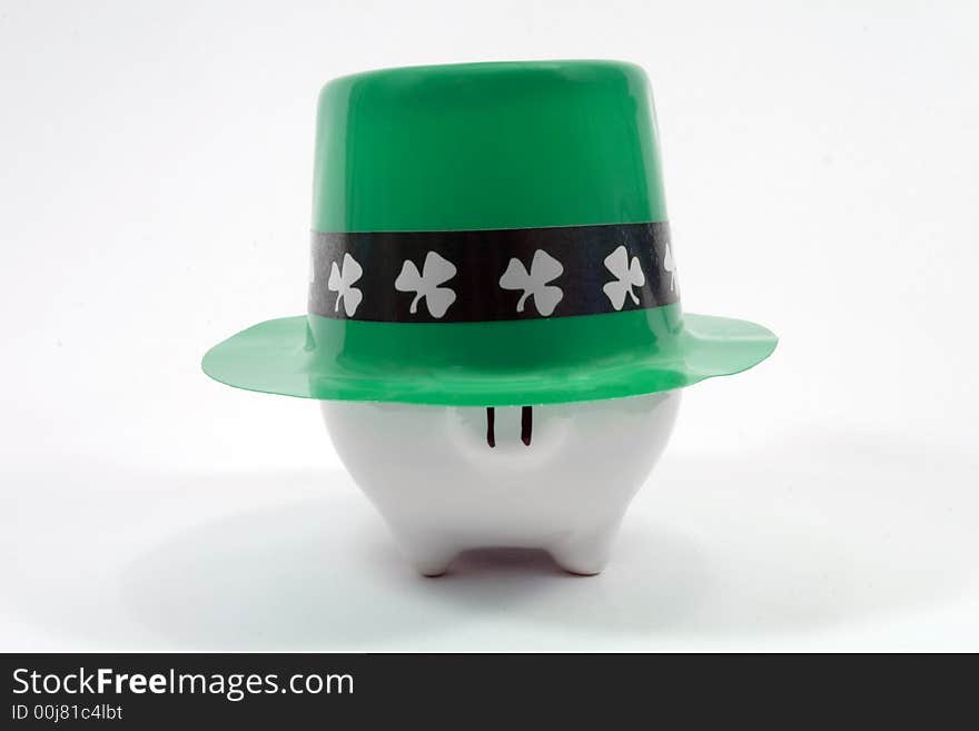 White piggy bank wearing a Saint Patrick's Day hat. Photographed on a white fabric background. White piggy bank wearing a Saint Patrick's Day hat. Photographed on a white fabric background.