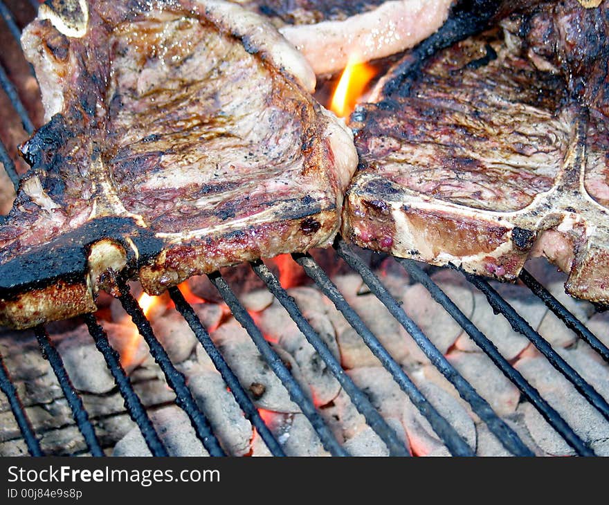 Grilling the T-Bone Steak, with flame and charcoal, nearly done. Grilling the T-Bone Steak, with flame and charcoal, nearly done.