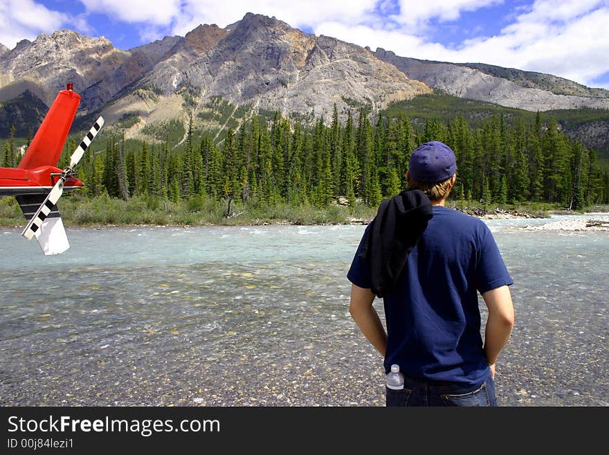 Young man enjoying remote wilderness after helicopter flight. Young man enjoying remote wilderness after helicopter flight.