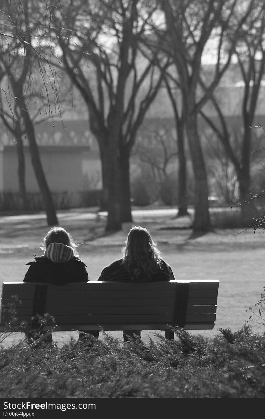 Black and white portrait of two woman enjoying a park from a bench. Black and white portrait of two woman enjoying a park from a bench.