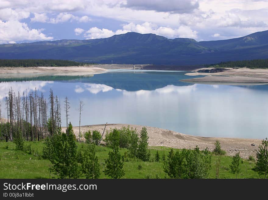 Beautiful blue and completely still lake reflecting the sky and surrounding mountains. Beautiful blue and completely still lake reflecting the sky and surrounding mountains