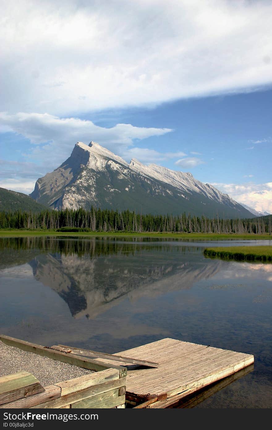 Mountain reflection with dock in foreground.