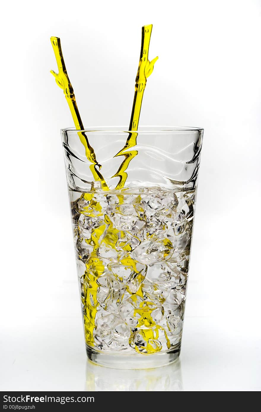 Cold drink with ice and yellow stirring rod isolated on white background