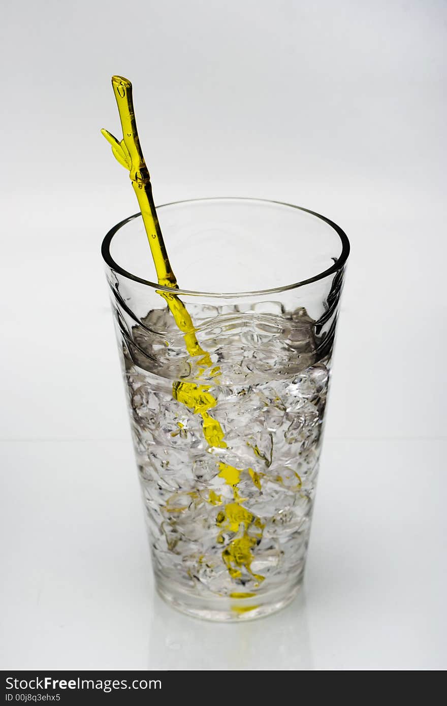 Cold drink with ice and yellow stirring rod isolated on white background