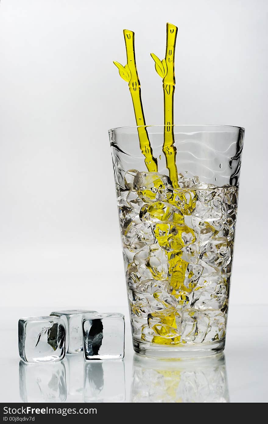 Cold drink with ice and yellow stirring rod isolated on white background