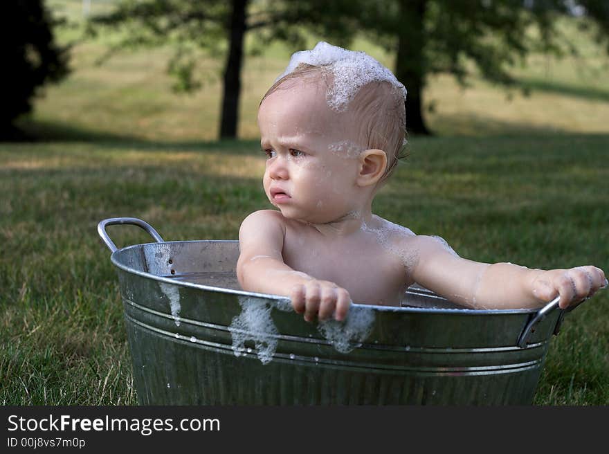 Image of cute toddler sitting in a tub outside. Image of cute toddler sitting in a tub outside