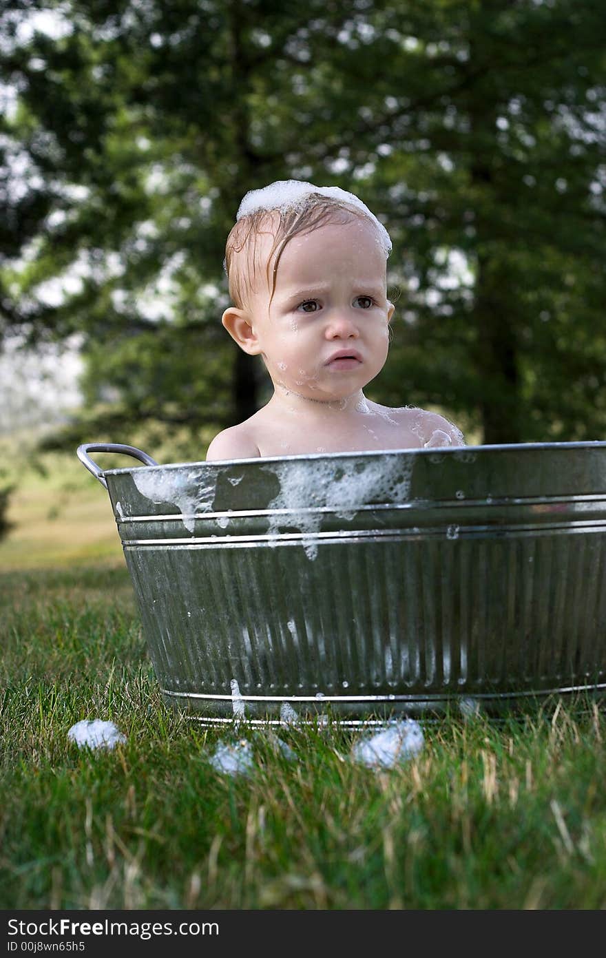 Image of cute toddler sitting in a tub outside. Image of cute toddler sitting in a tub outside