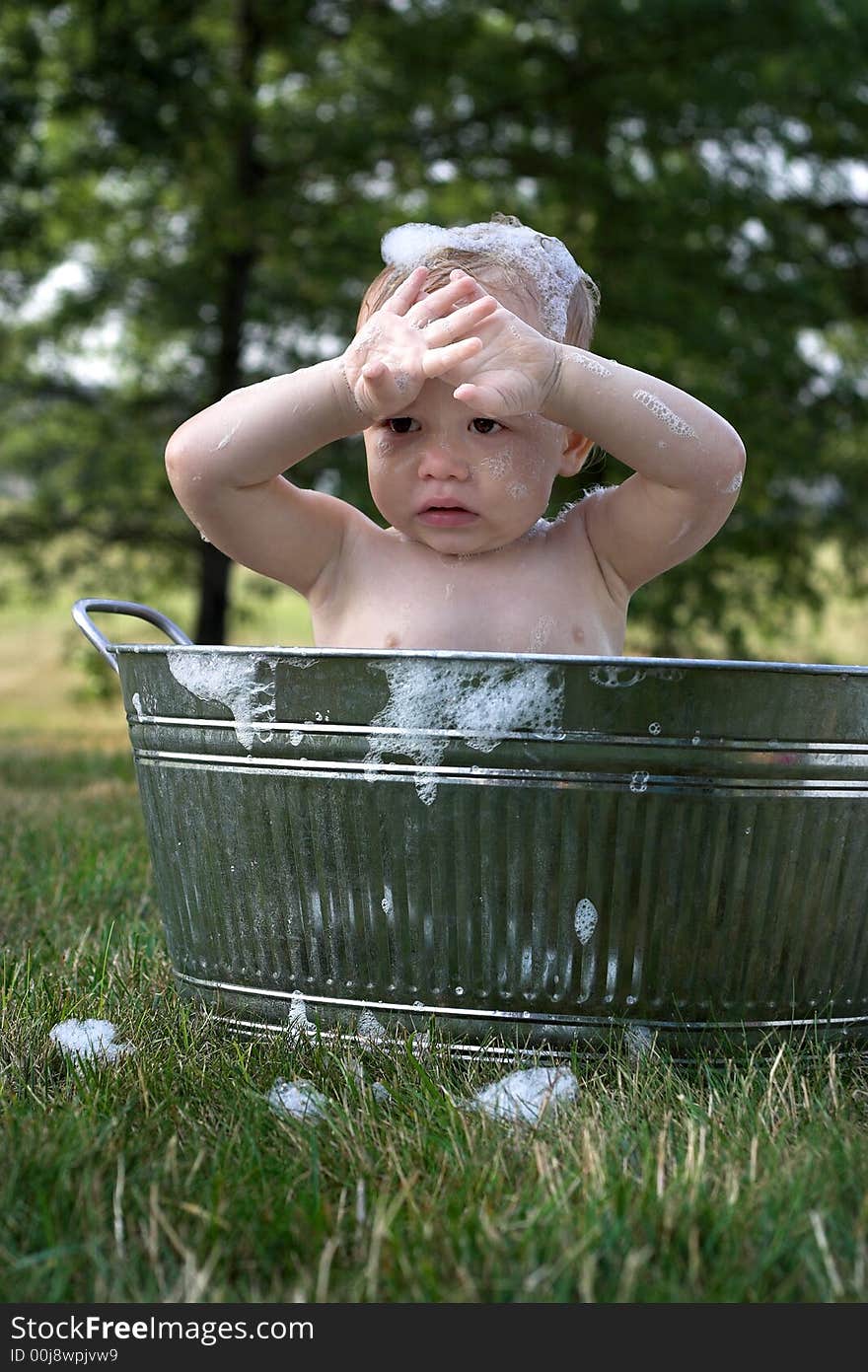 Image of cute toddler sitting in a tub outside. Image of cute toddler sitting in a tub outside