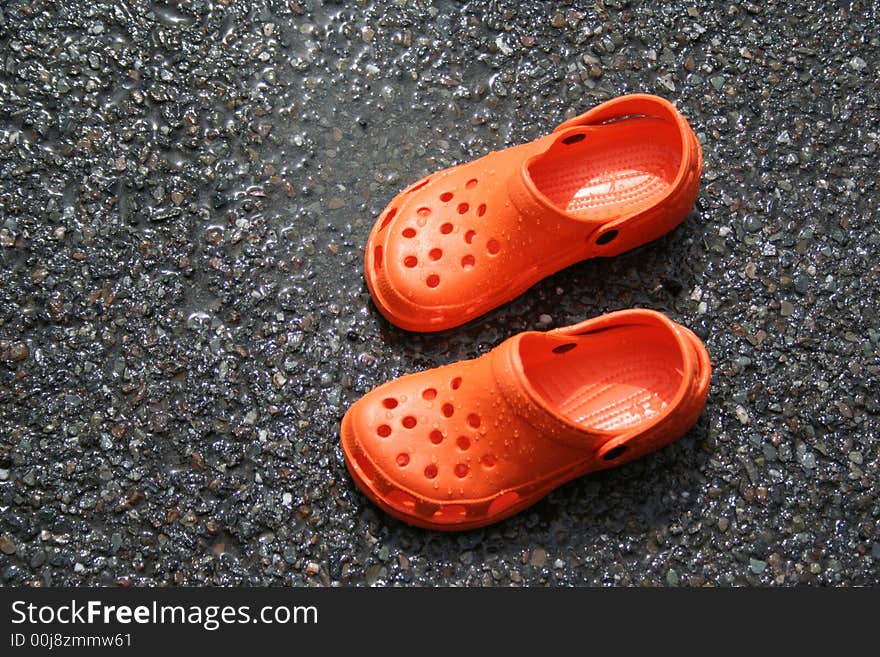 Wet orange clogs on asphalt