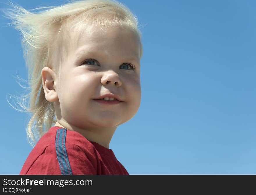 The blue-eyed boy with blond hair developing on a wind