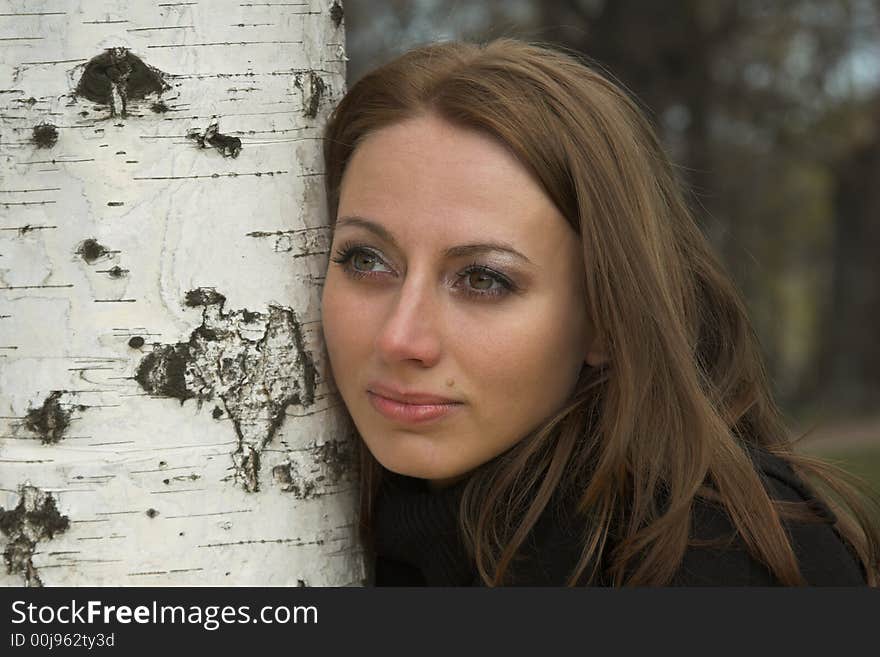 Beautiful woman about a tree looks afar. Beautiful woman about a tree looks afar