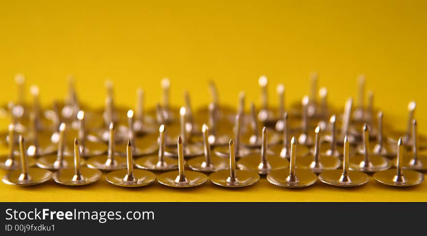 Thumb tacks nickel plated on a yellow background