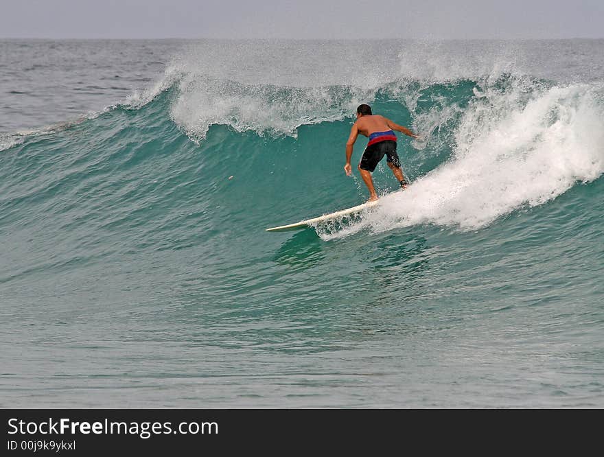 A longboarder takes off on a clean wave in Phuket, Thailand. A longboarder takes off on a clean wave in Phuket, Thailand