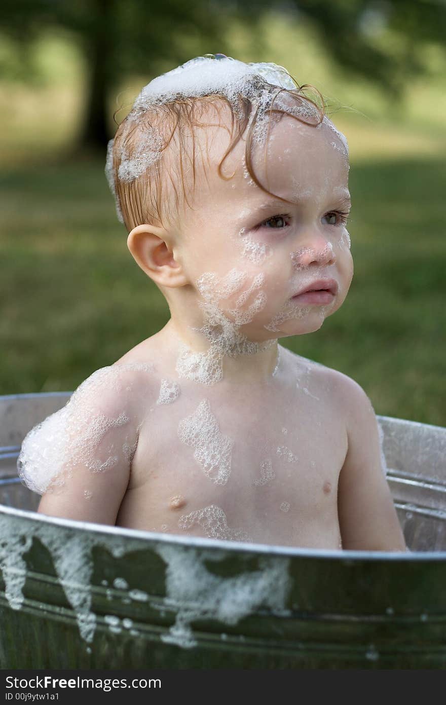 Image of cute toddler sitting in a tub outside. Image of cute toddler sitting in a tub outside