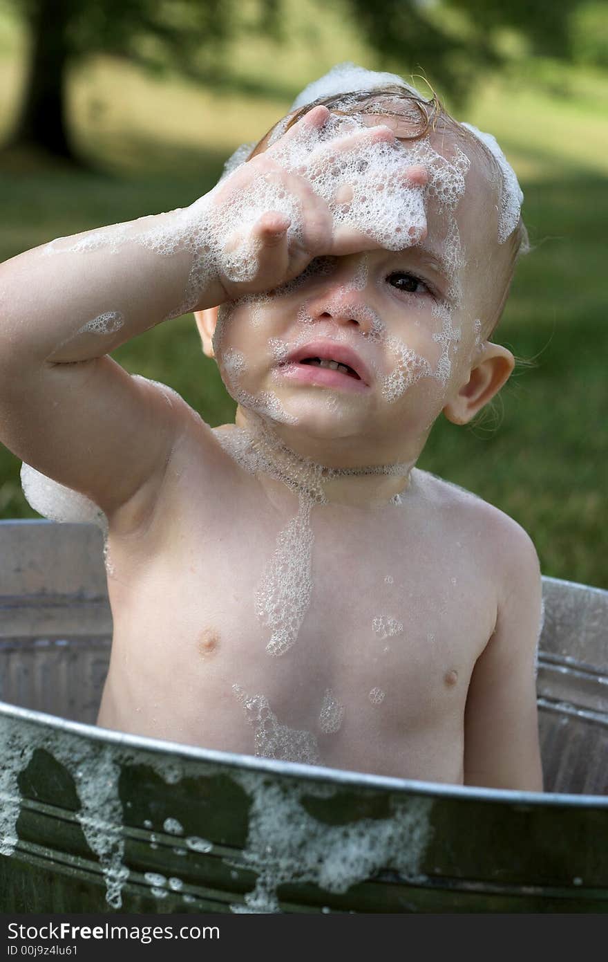 Image of cute toddler sitting in a tub outside. Image of cute toddler sitting in a tub outside