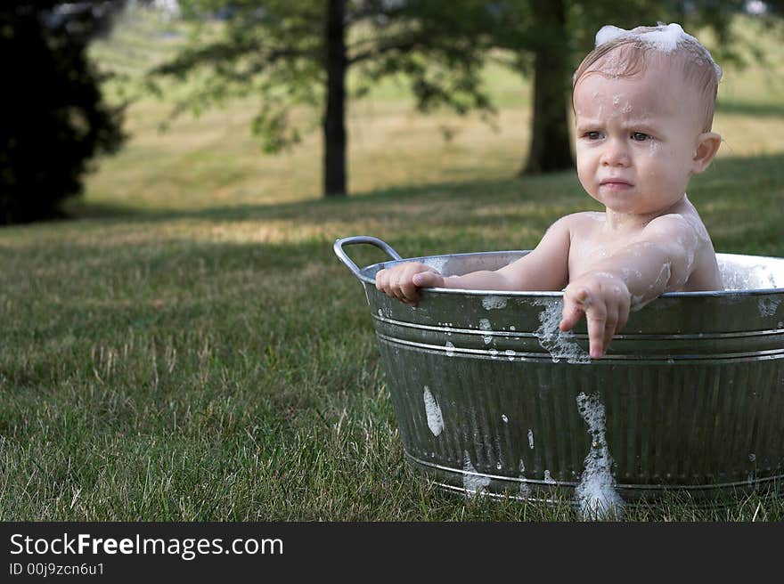 Image of cute toddler sitting in a tub outside. Image of cute toddler sitting in a tub outside