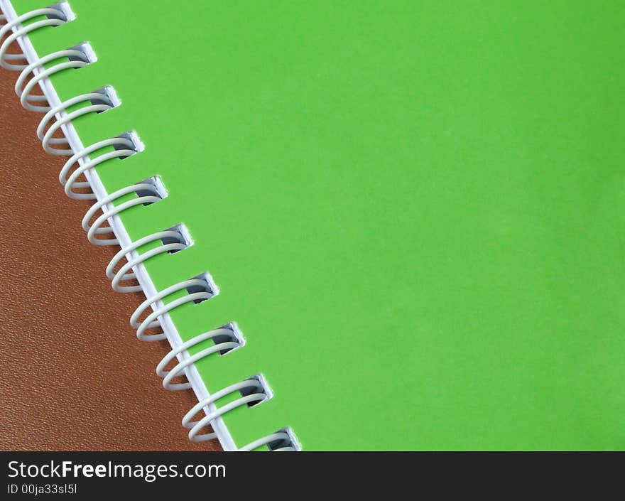 A green cover of a spiral notebook on a leather background