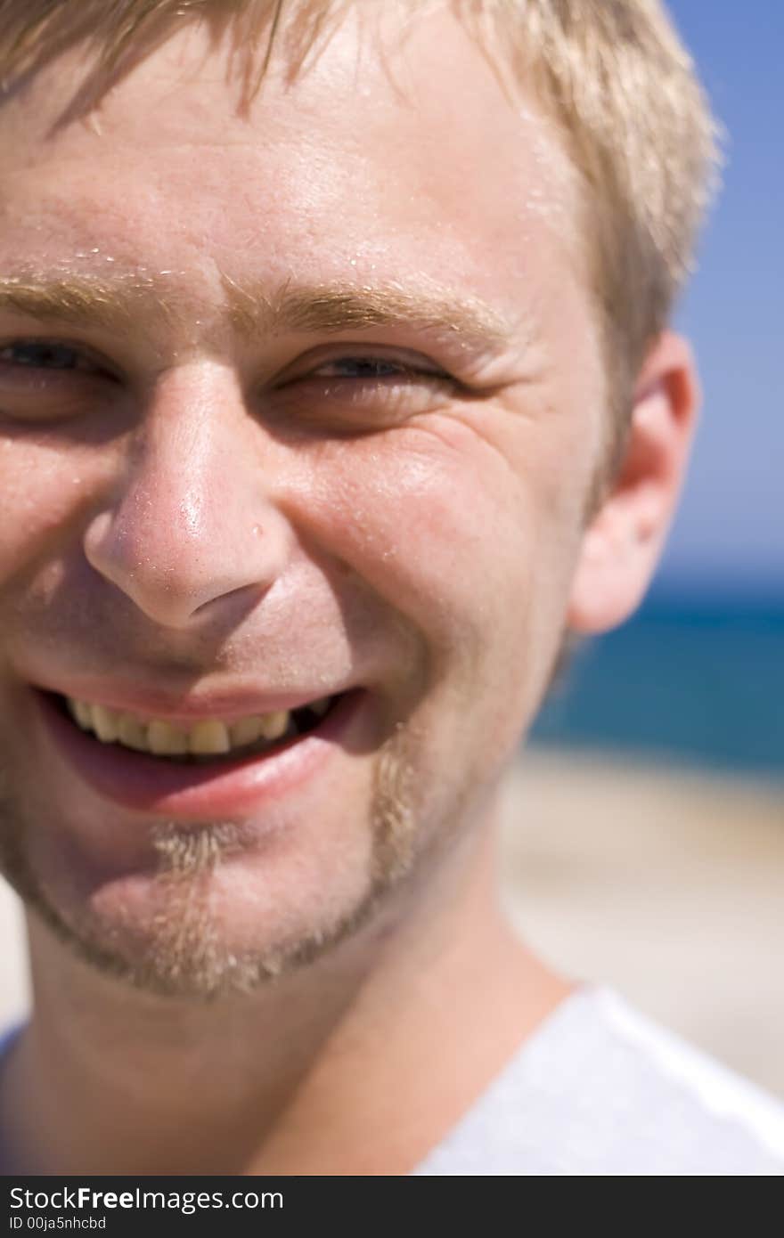 The man with a small beard laughs at a background of the sea. The man with a small beard laughs at a background of the sea