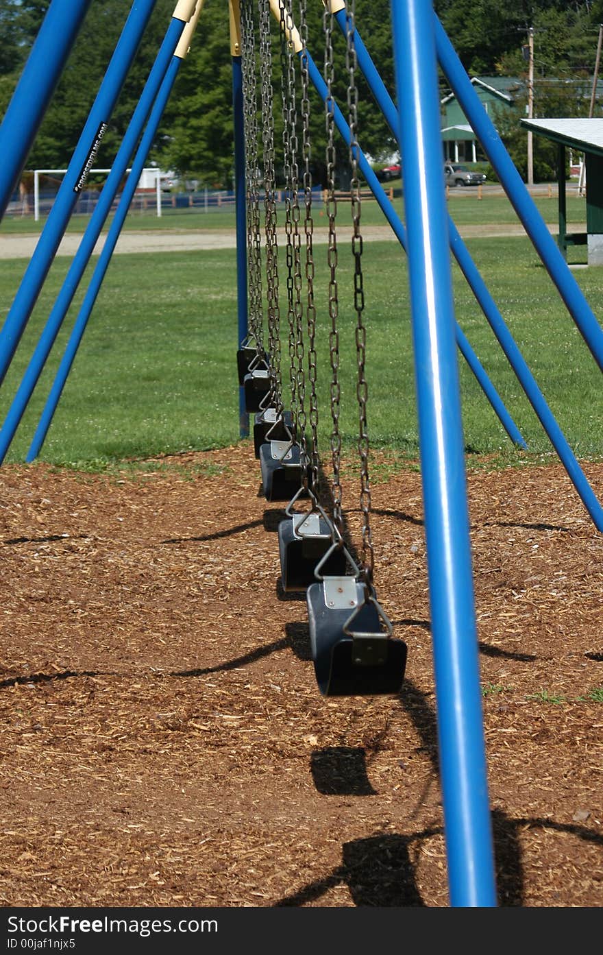 A blue swing set on a playground in the park. A blue swing set on a playground in the park