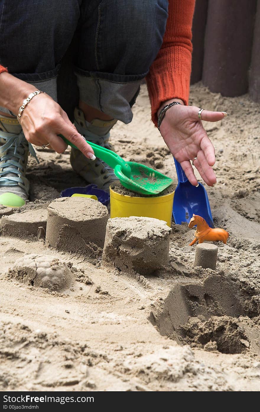 Woman making sand shapes with toy molds and plastic shovel. Woman making sand shapes with toy molds and plastic shovel