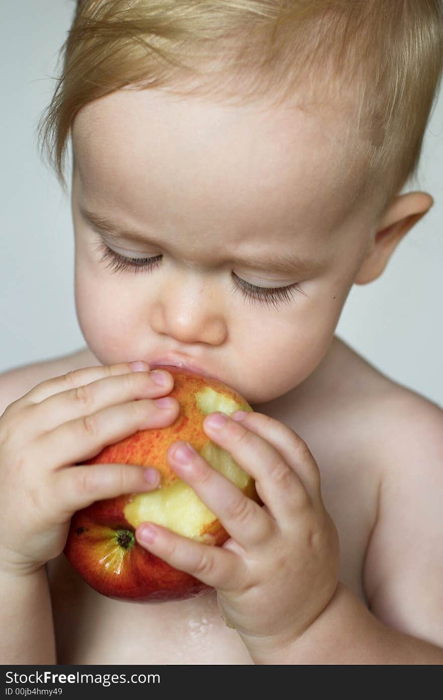 Image of cute toddler eating an apple. Image of cute toddler eating an apple