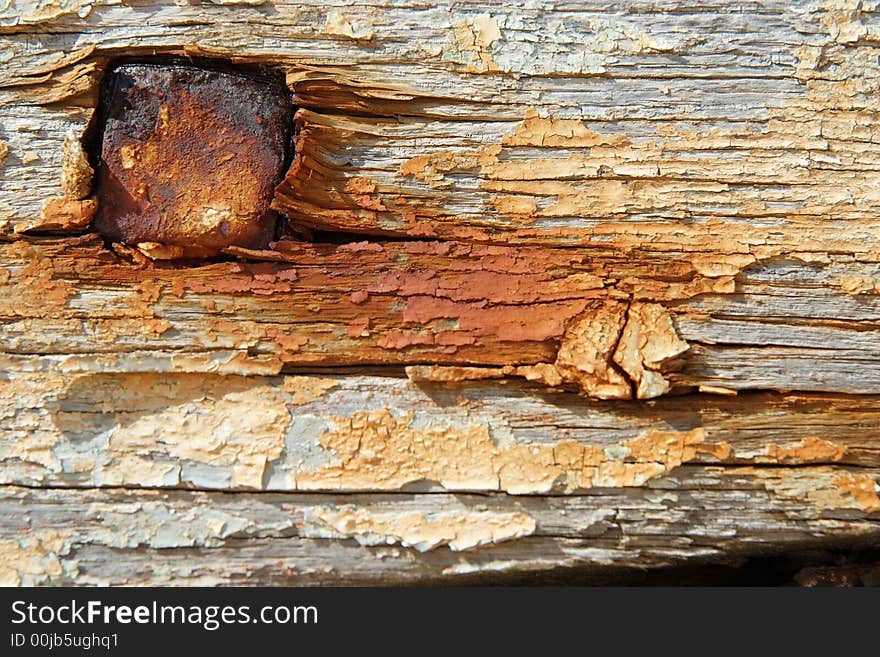 Some old painted and rusty boards in a boat cemetary with a large nail. Some old painted and rusty boards in a boat cemetary with a large nail