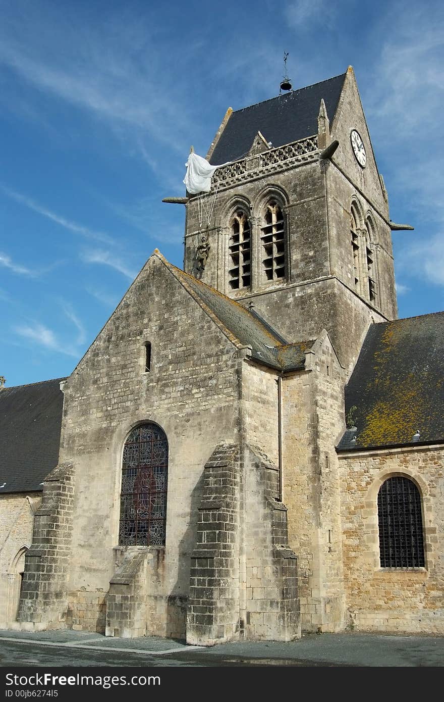 Sainte Mere Eglise was the first town liberated by the Allies just before H-Hour on D-Day. The town was the scene of a famous incident where American paratrooper John Steele had his parachute caught on the spire of the church. There is a dummy and parachute hanging on the church to commemorate this story (Normandy - France). Sainte Mere Eglise was the first town liberated by the Allies just before H-Hour on D-Day. The town was the scene of a famous incident where American paratrooper John Steele had his parachute caught on the spire of the church. There is a dummy and parachute hanging on the church to commemorate this story (Normandy - France)