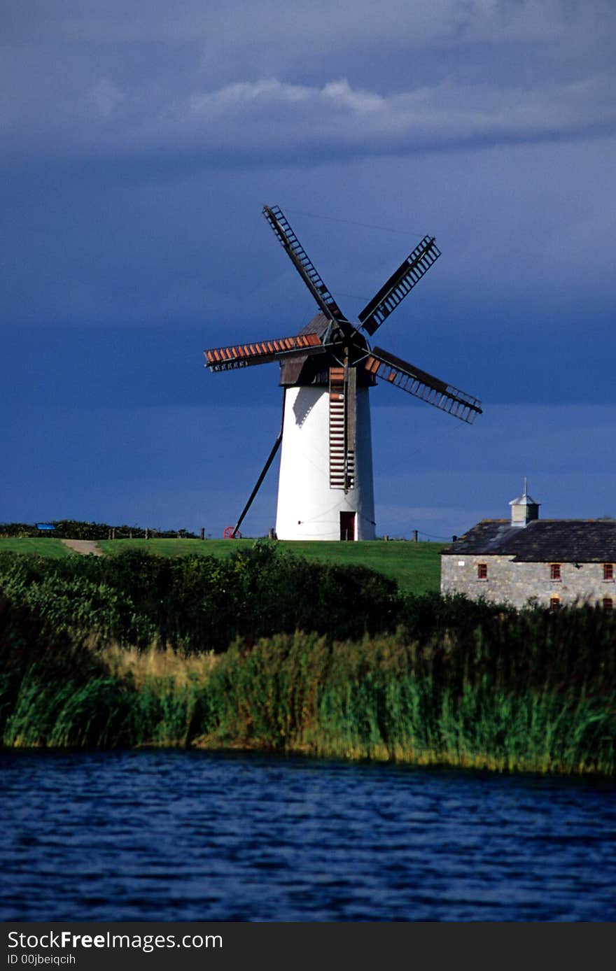 Windmill in Skerries, Dublin, Ireland with a pond and old building in the foreground. Windmill in Skerries, Dublin, Ireland with a pond and old building in the foreground.