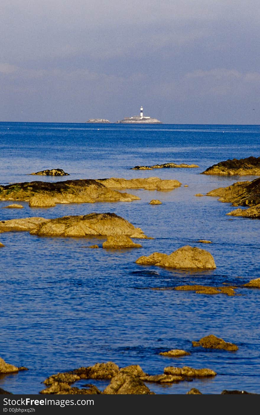 Rockabill Lighthouse, Skerries, Dublin, Ireland with rocks and ocean in the foreground.