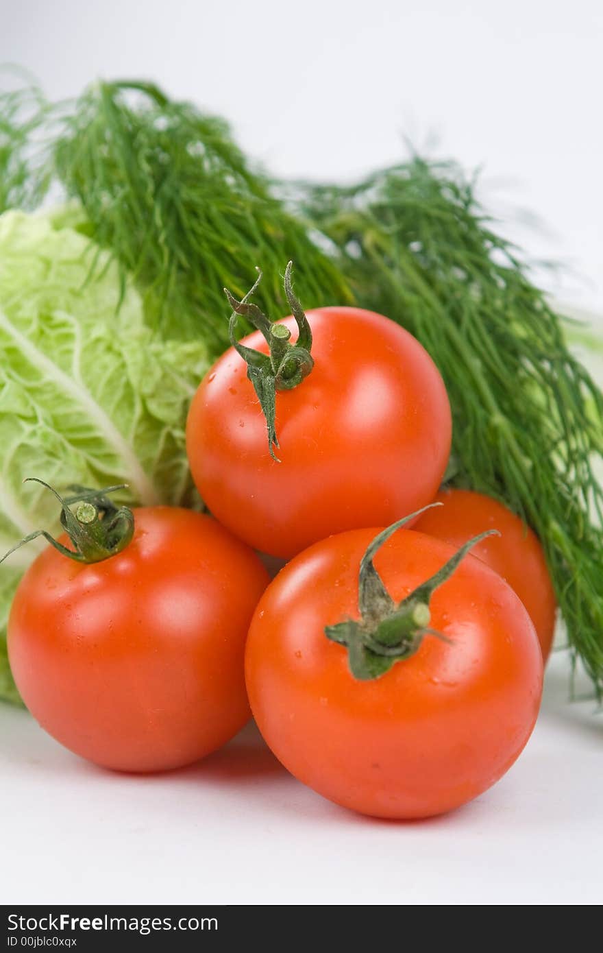 Pile of tomatoes with lettuce and dill on the background