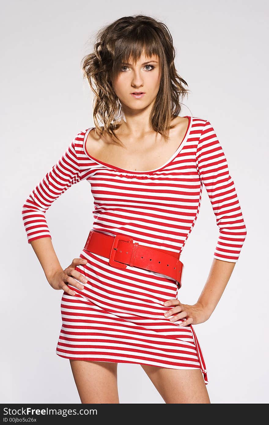 Brunette woman on light background wearing red and white striped blouse