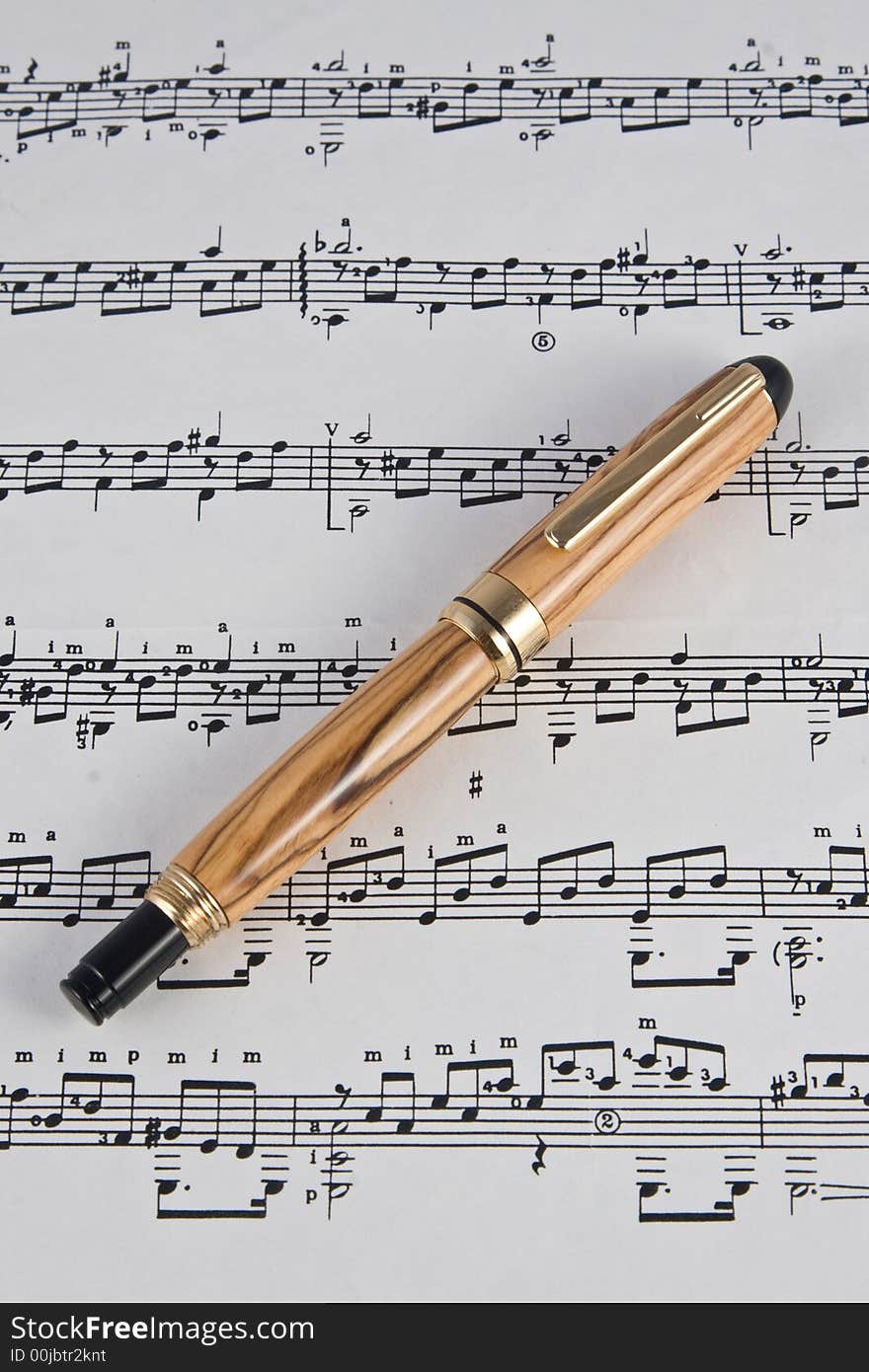 A handmade fine writing instrument made from Bethlehem Olive Wood displayed on a sheet of music. (The pen was handmade by the photographer in his studio).