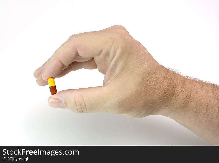 Male hand holding a two-colored pill for medicine. Male hand holding a two-colored pill for medicine.