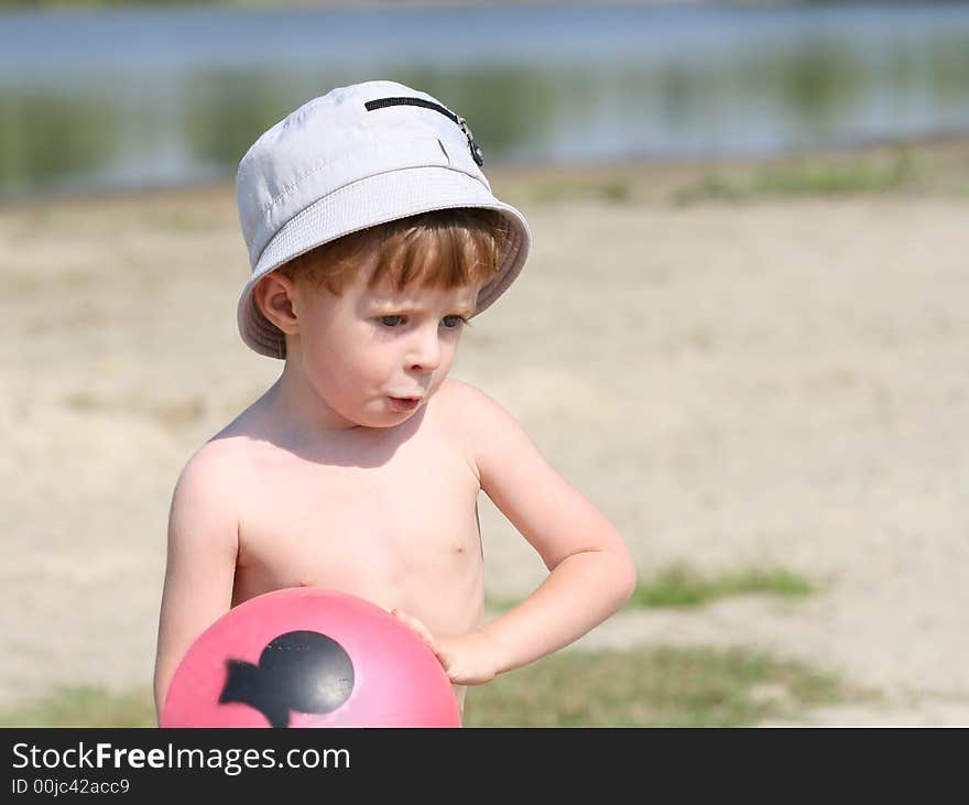 The boy on a beach holds a ball in hands. The boy on a beach holds a ball in hands