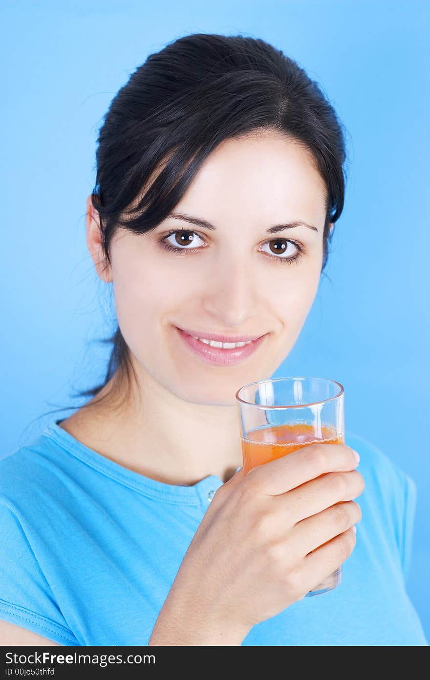 Young girl drinking juice on blue background