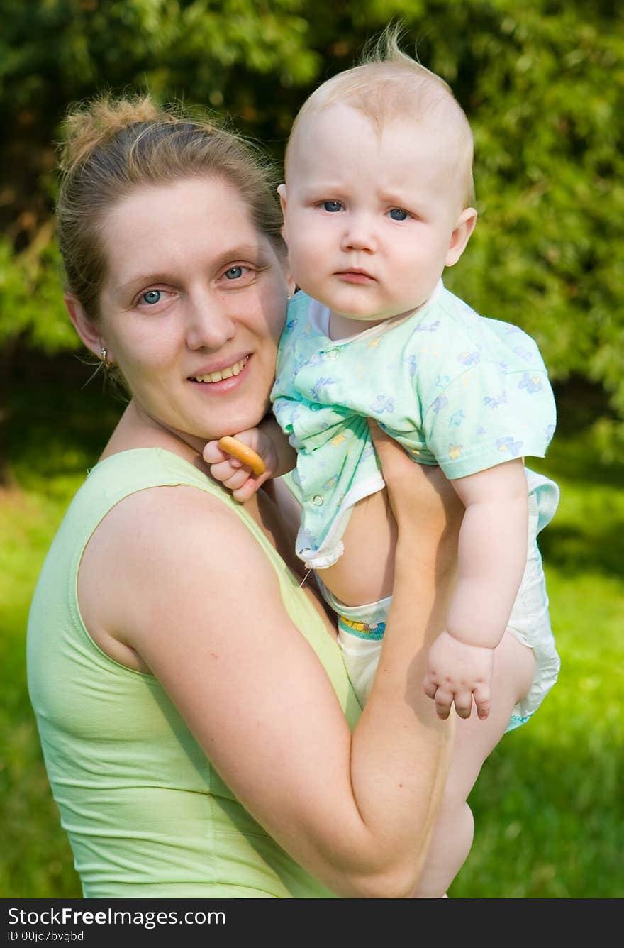 Portrait of mother with the child on hands on a background of green foliage. Portrait of mother with the child on hands on a background of green foliage