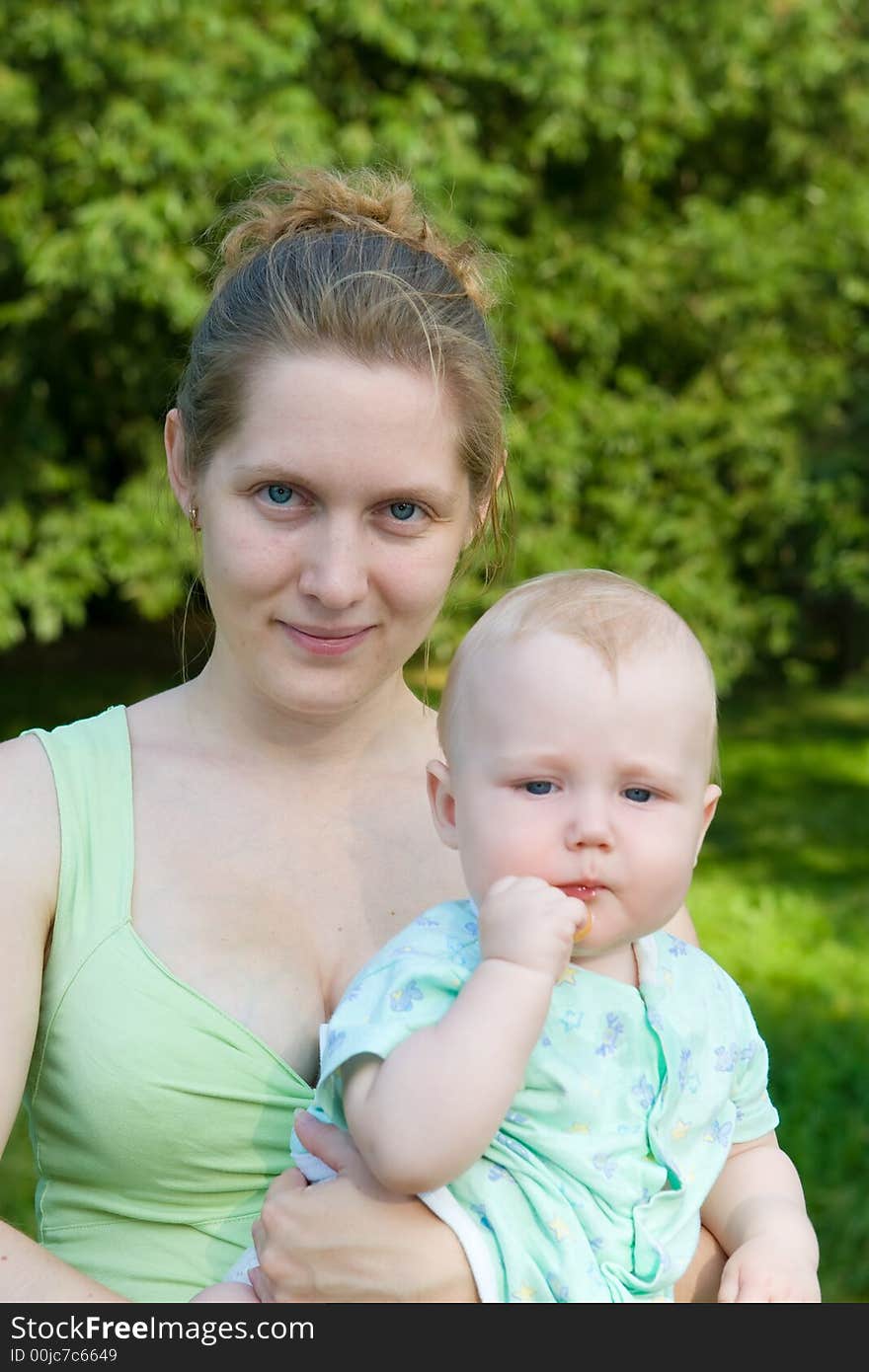 Portrait of mother with the child on hands on a background of green foliage. Portrait of mother with the child on hands on a background of green foliage