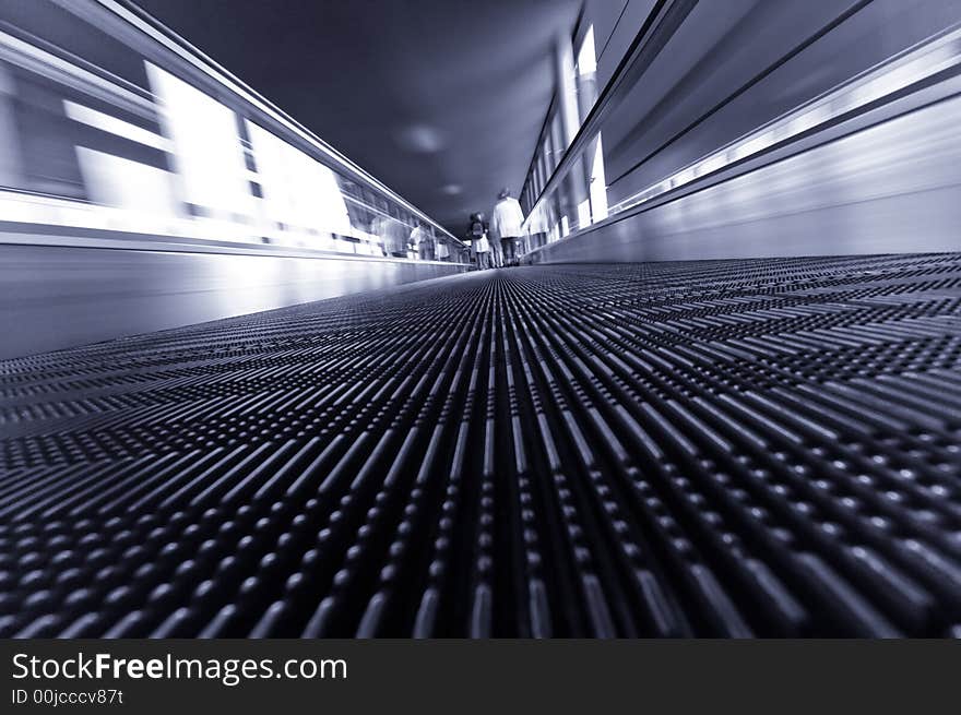 Abstract image of people traveling on a moving escalator at airport taken with an ultra wide angle lens